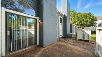 A grey house with a glass door and a small garden.